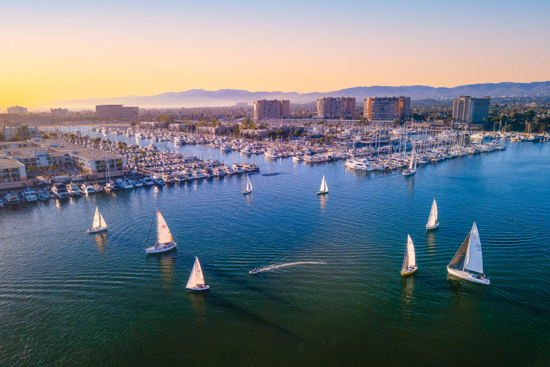 Aerial view of Marina del Rey harbor with sailboats and waterfront residences at sunset